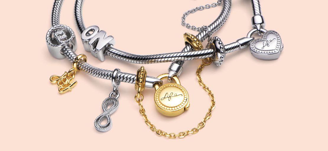 Corrente de segurança dourada da Vivara colocada em uma pulseira prata com pingentes.