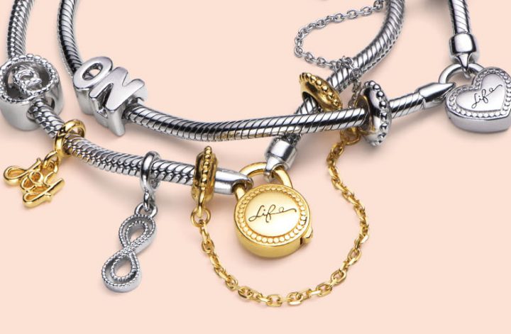 Corrente de segurança dourada da Vivara colocada em uma pulseira prata com pingentes.