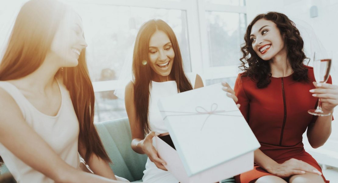 Mulheres felizes e rindo trocando presentes e abrindo um presente.