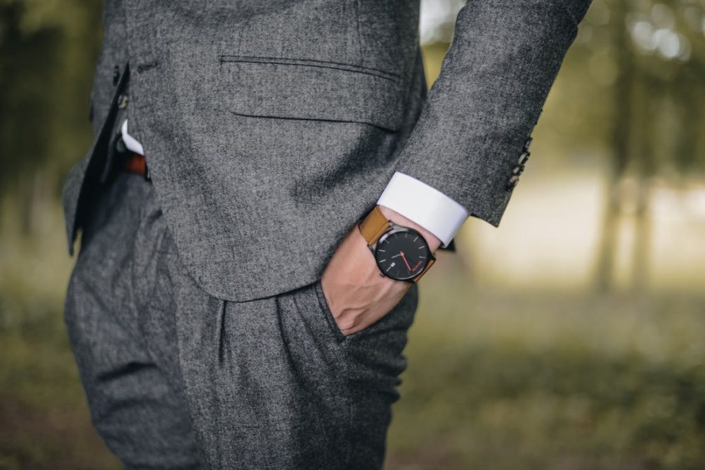 Homem usando um look masculino para casamento, um terno cinza e relógio.