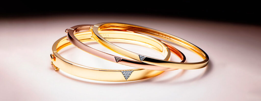 três pulseiras Vivara, dispostas sobre uma mesa clara. Elas são feitas em Ouro Amarelo e Ouro Rosé, e contam com aplicações delicadas em pedras preciosas