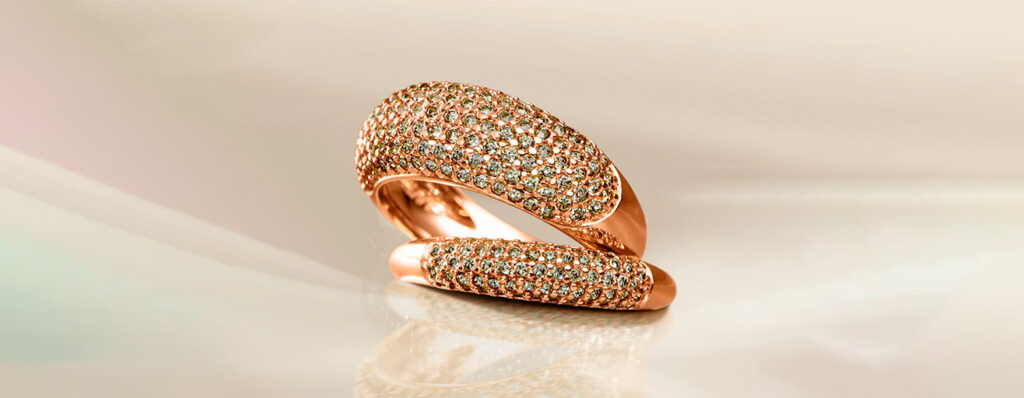 na imagem, dois anéis Vivara em Ouro Rosé e Cravejamento de Diamantes posam sobre um fundo claro e luminoso