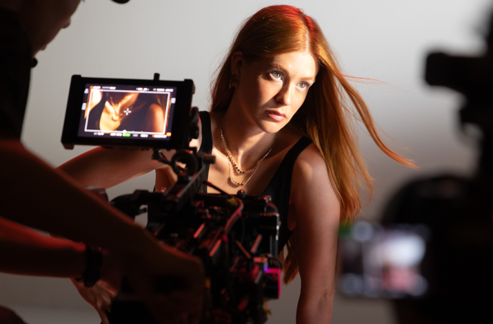 Marina Ruy Barbosa posando com confiança durante o making of da campanha de Dia das Mães Life By Vivara 2025, enquanto o fotógrafo ajusta a câmera para capturar a imagem. Ela usa joias delicadas e um look sofisticado, com os cabelos soltos e ao vento.